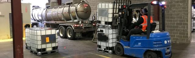forklift moving filled totes in warehouse