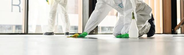 People in PPE cleaning building floor
