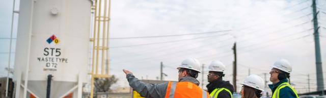 group of people touring worksite with large waste storage tanks