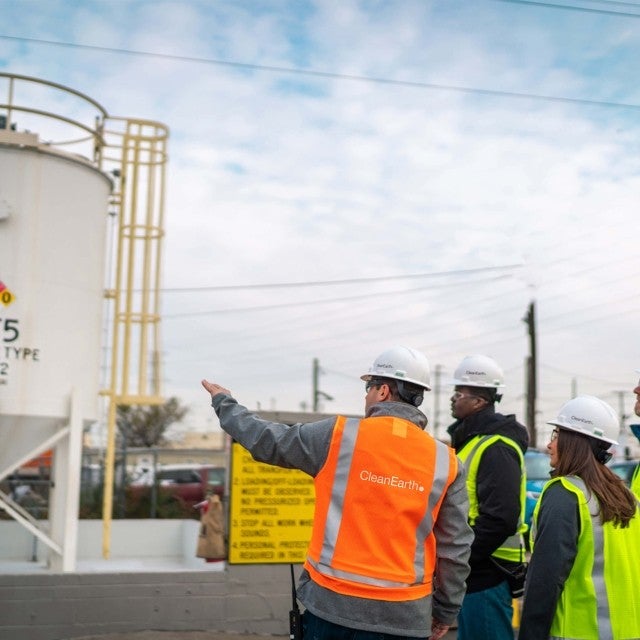 group of people touring worksite with large waste storage tanks