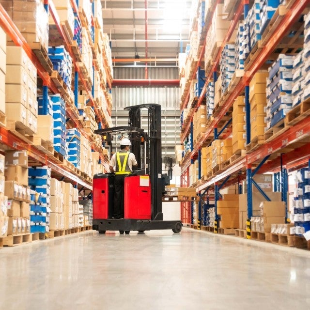 Person on forklift between retail warehouse shelves 