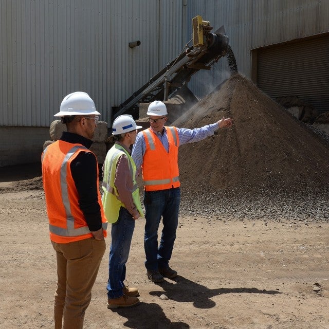 three men in safety vests touring soil facility