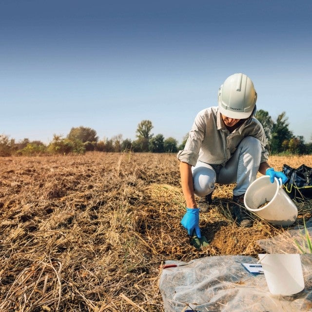 woman in field collecting soil sample