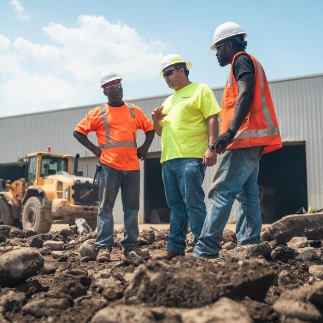 three men talking on soil worksite