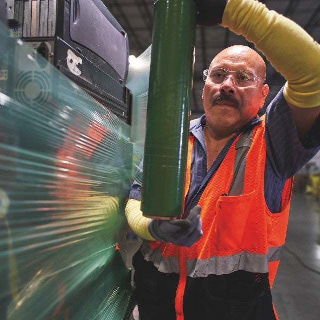 man shrink-wrapping pallet of electronics