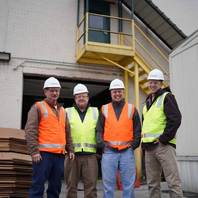 Four people posing outside warehouse 