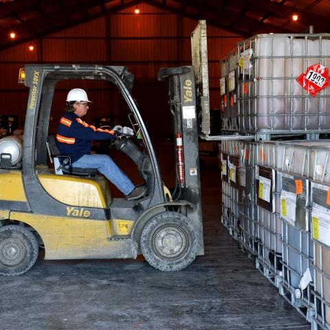 man on forklift moving large totes