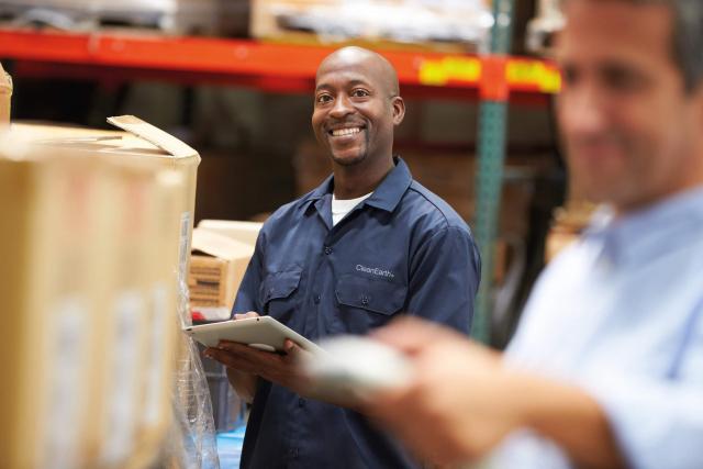 man smiling in warehouse doing inventory