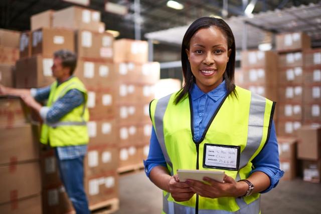 Team member in safety vest with tablet in warehouse