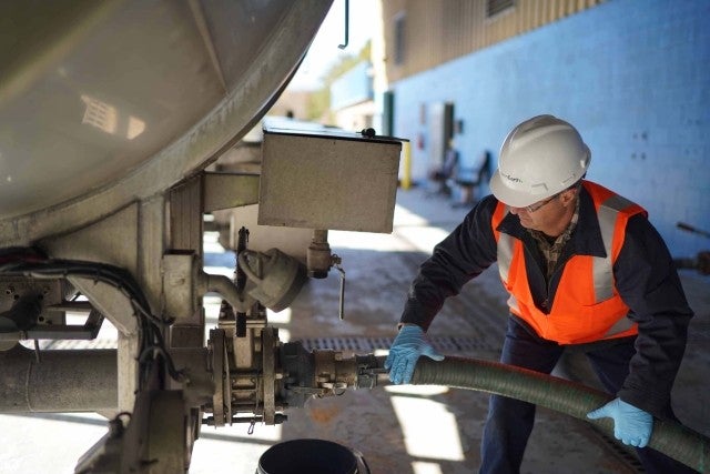 man using a hose to remove wastewater from transport vehicle