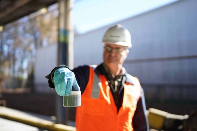 Man holding small container of sample in facility