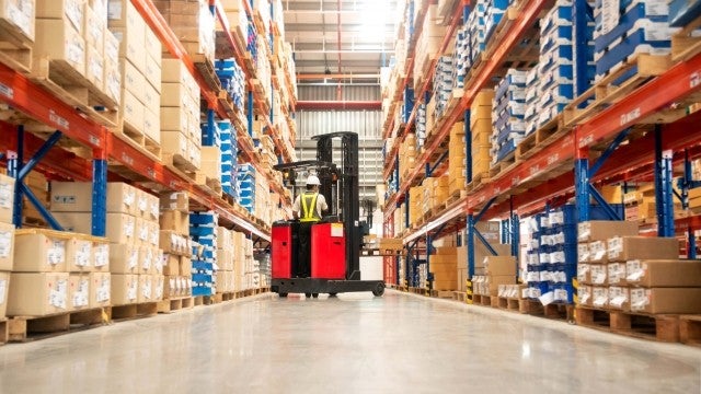 Person on forklift between retail warehouse shelves