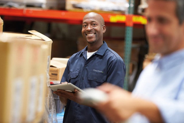 man smiling in warehouse doing inventory